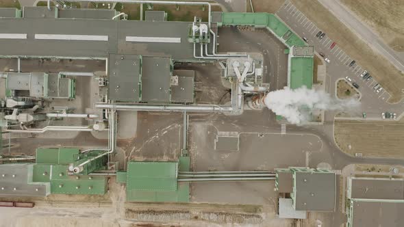 Aerial Top Down View of Woodworking Plant Near Pine Forest, High Chimney Smoke, Large Stocks of Wood