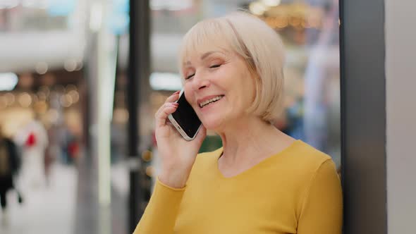 Smiling Happy Middle Aged Mature Woman Talking Speaking on Mobile Phone Making Order Uses Smartphone