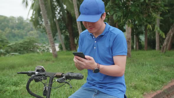 Delivery Asian Man Courier Using Mobile Phone With Electric Scooter And Packages For Customers