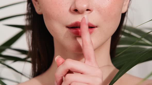 A close-up view of a woman's lips while she doing secret gesture