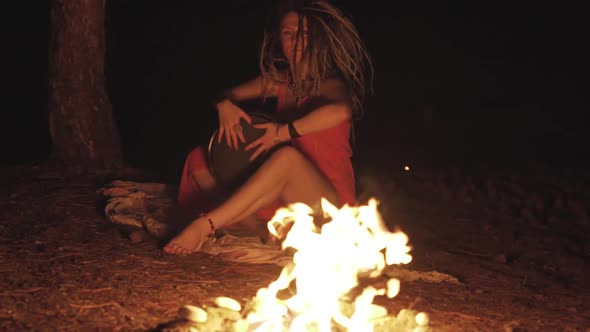 Beautiful Young Hippie Woman with Dreadlocks Playing on Djembe