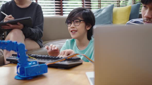 Asian kids program robotic cranes with laptops to learn about technology