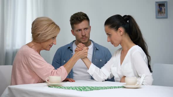 Man Looking at Mother and Wife During Arm Wrestling Competition, Family Fight