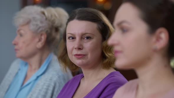 Closeup of Happy Caucasian Adult Woman Turning to Camera Smiling with Blurred Daughter and Mother on