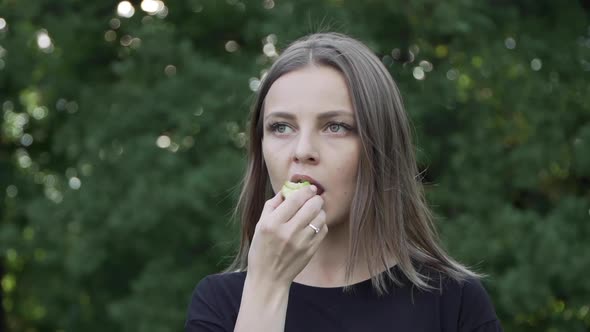 Young Girl Eating an Apple in the Summer Forest