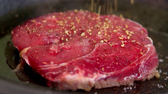 On a Hot Frying Pan is a Piece of Fresh Marbled Beef Steak Sprinkled with Various Steak Spices Salt