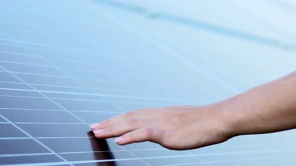 Close up of young woman engineer's hands touching solar panels. Solar energy.