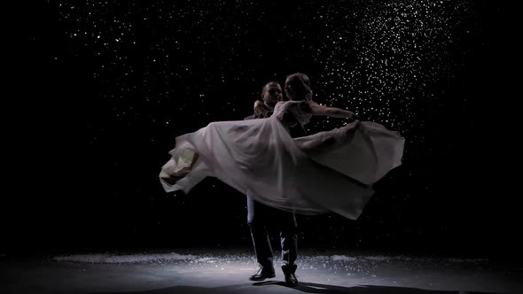 Tender Couple in Love on the Background of Falling Snow. A Man Is Circling in His Arms His Beloved