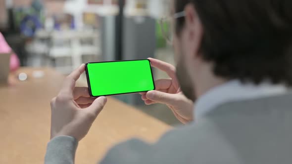 Man Looking at Smartphone with Green Chroma Screen