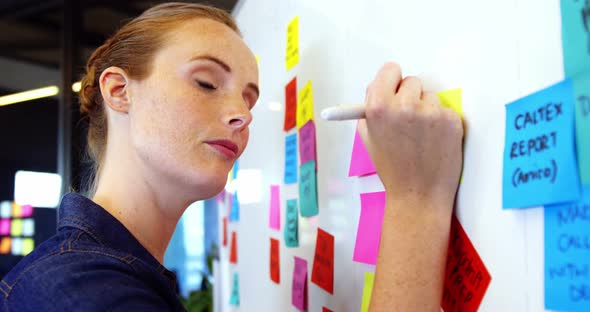 Female business executive writing on sticky notes