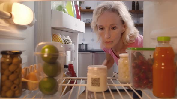 Mature Woman Taking Yogurt From Refrigerator in Kitchen