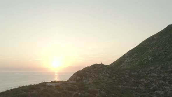 Panning shot of mountain revealing sun rising over the horizon