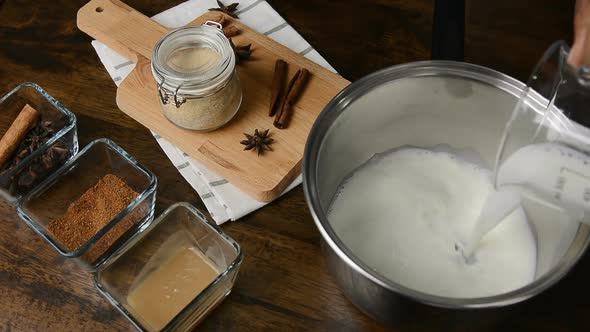 Milk being poured into the stainless steel pot for cooking in kitchen