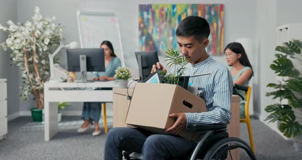 Disabled Man Dressed in Shirt Got Job in Company's Office He is Sitting in Wheelchair Holding Box