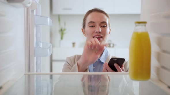 Online ordering of goods from the supermarket. Woman in suit looks into an empty refrigerator