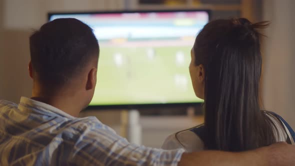 Back View of Millennial Couple Watching Football on Tv Relaxing at Home
