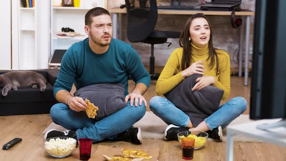 Disappointed Couple Sitting on the Floor While Watching Sport