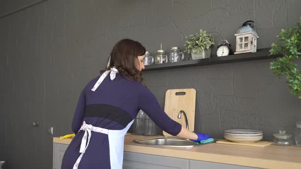 Woman in Rubber Gloves Cleaning Kitchen Worktop