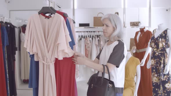 Focused Shop Customer Browsing Clothes on Rack