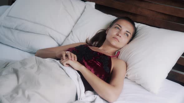 Young Woman Sleeps, Opens Her Eyes, Wakes Up, Stretches in Bed and Smile