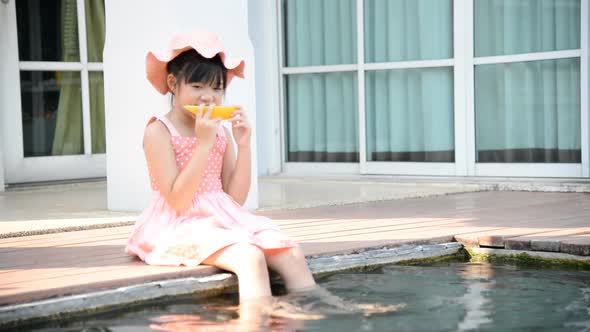 Little Asian Girl Eating Melon and Splashing Around In The Pool