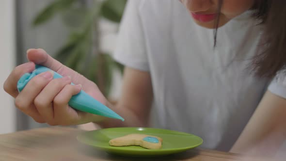 Cute Asian girl drawing on biscuit cookie for make delicious dessert, Home school cooking class.