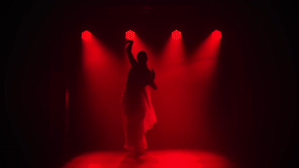 Silhouette a Young Girl Dancer in a Red Sari. Indian Folk Dance. Shot in a Dark Studio with Smoke