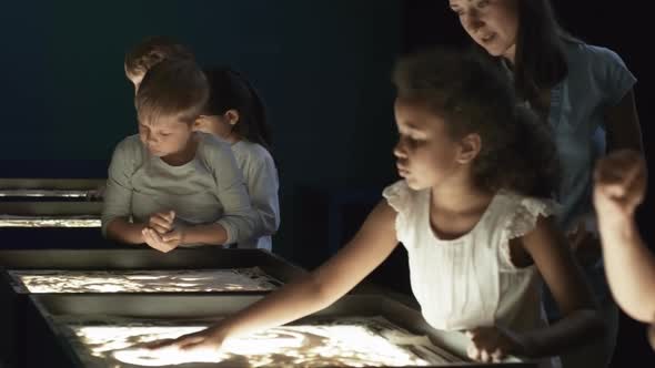 Cheerful Teacher Talking to Girl Making Sand Animation