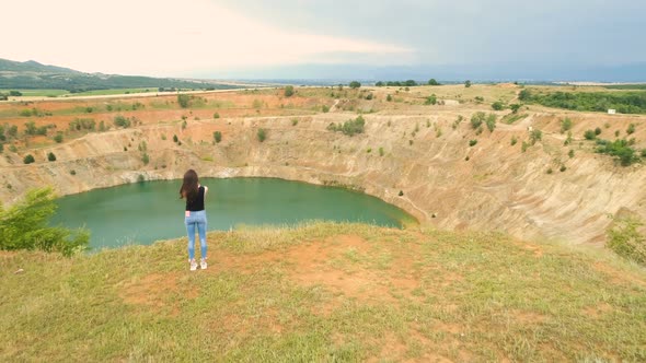 Lonely Woman Taking Photos of Open Mine Pit Filled with Blue Water in Tsar Asen Village, Bulgaria