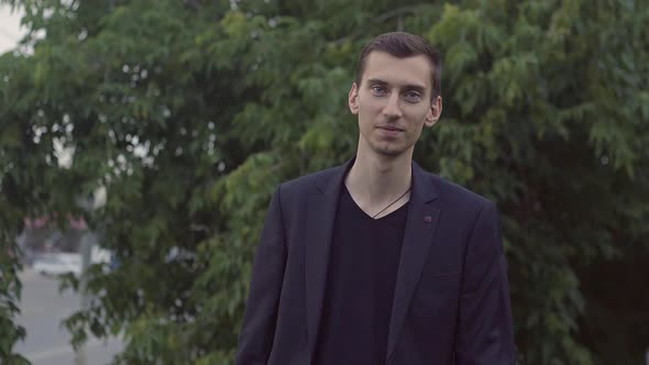 a Young Guy in a Jacket Holds a Glass and Dances