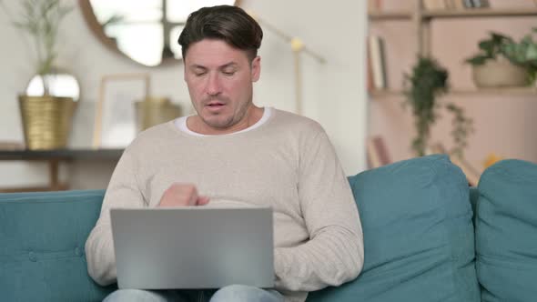 Middle Aged Man with Laptop Coughing at Home 