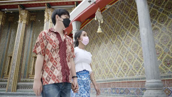 A Lovely International Couple in Protective Masks Travel Together Walking and Chatting Inside Wat