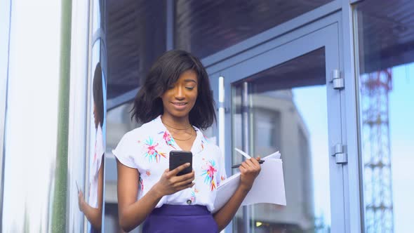 Elegant Beautiful African American Businesswoman Using Social Networks on Her Smartphone and Holds