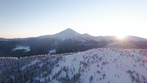 Flying Towards Mountain Ridge With Sun Illuminated Tree Tops