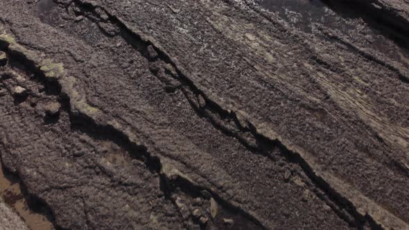 Aerial drone view flying over the stony shoreline of St Andrews Bay, tilting up from the rocks to re