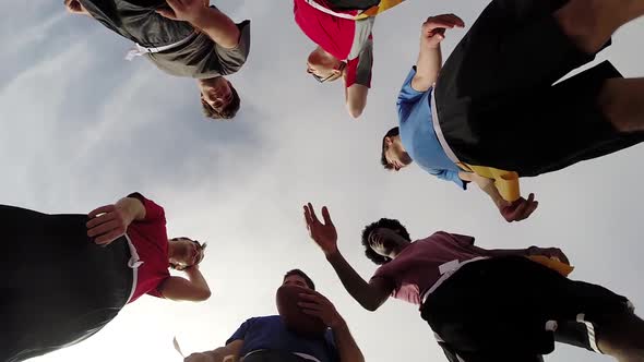 A group of young men playing flag football on the beach.