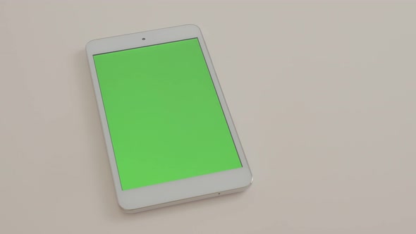Silver tablet-pc with green screen display slow panning on white background 4K 2160p UltraHD footage