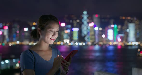 Woman use of smart phone in city at night