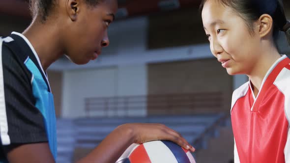 Volleyball players standing face to face with volleyball 