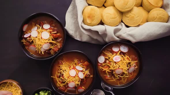 Step by step. Garnishing turkey chili with green onions, radishes, and cheddar cheese.