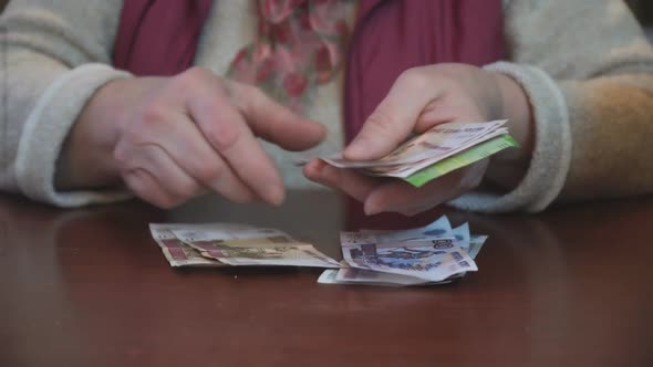 The Woman Counts and Lays Out the Money Sitting at Table