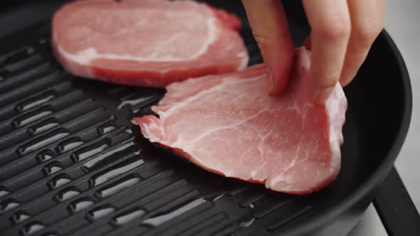 Crop person frying pork chops in pan in kitchen