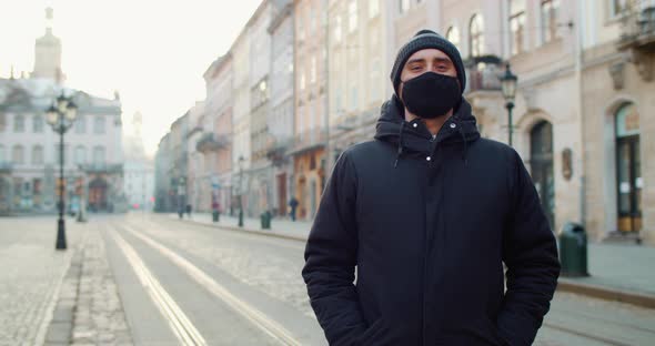 Portrait of Man in Black Protective Cotton Mask Standing at Empty Street of Old Europian City