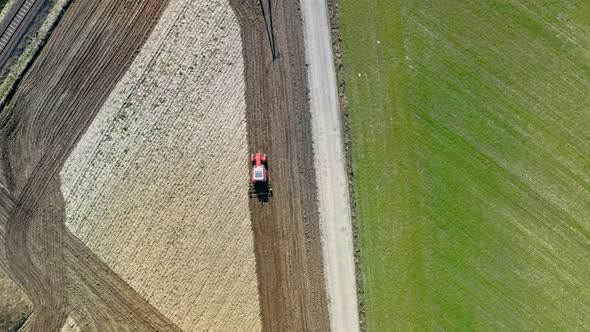 Red tractor plowing field in Poland, aerial view in spring