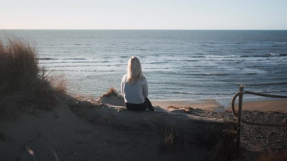 Woman Sitting Alone On Sunlit Beach