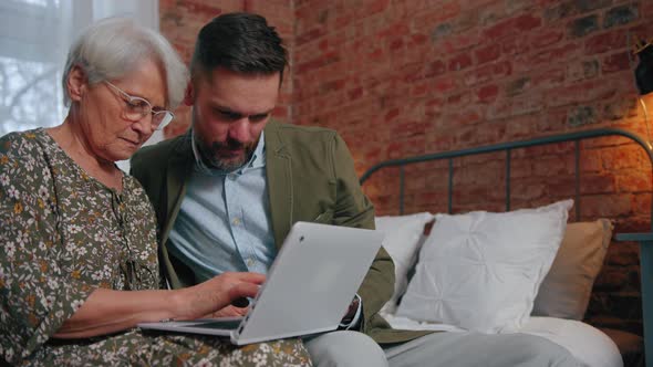 Middleaged Caucasian Man Helping His Grandmother with the Usage of Computer