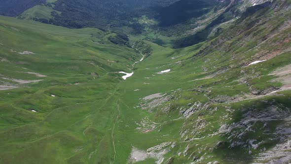 Flying Backward Over a Mountain Valley in Mountains of Adygea on Summer Day. Green Trees and Bushes