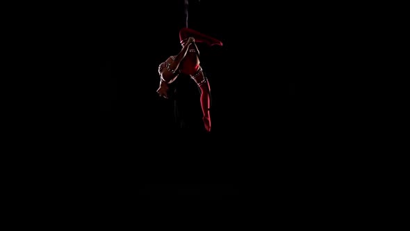 Two Women in Costumes Aerialists Spinning on a Hoop on Stage. Black Background. Slow Motion