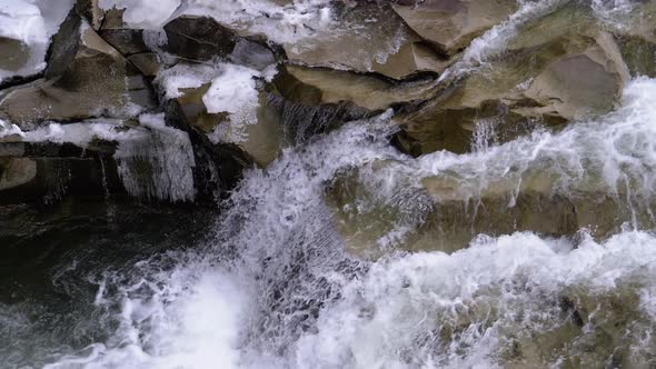 Mountain Creek and Stone Rapids with Snow. Rapid Flow of Water. Winter Waterfall. Slow Motion