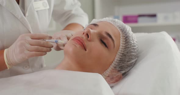 A Cosmetologist Makes an Injection of a Patient Face with Medical Preparations